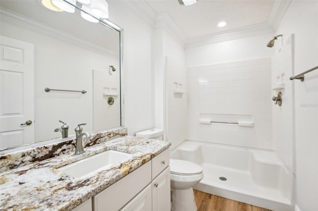 bathroom featuring vanity, crown molding, toilet, tiled shower, and wood-type flooring