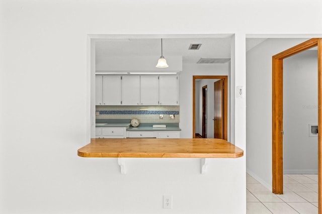 kitchen featuring decorative backsplash, wood counters, a breakfast bar, pendant lighting, and white cabinetry