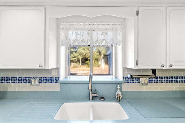 kitchen featuring decorative backsplash, white cabinetry, and sink