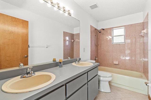 full bathroom featuring vanity, tiled shower / bath, tile patterned flooring, toilet, and a textured ceiling