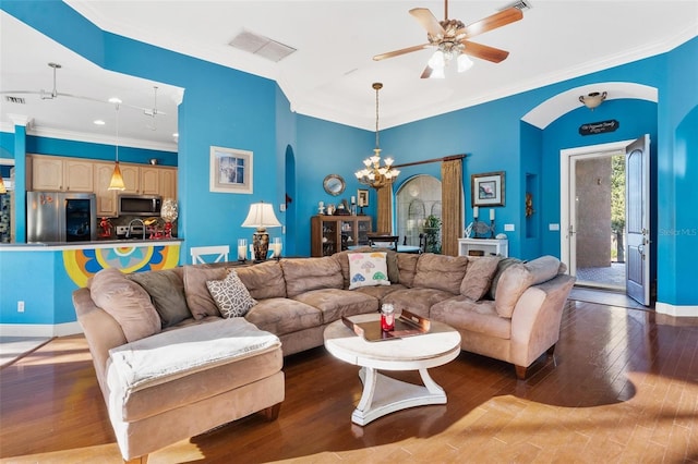 living room with ceiling fan with notable chandelier, hardwood / wood-style flooring, and ornamental molding