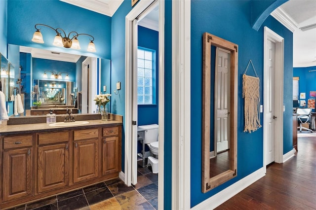 bathroom with crown molding, hardwood / wood-style floors, vanity, and toilet