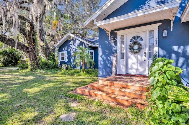 view of exterior entry with a yard