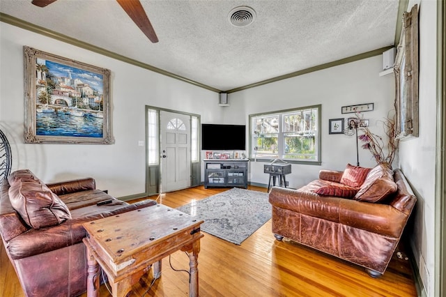 living room featuring ceiling fan, light hardwood / wood-style floors, ornamental molding, and a textured ceiling