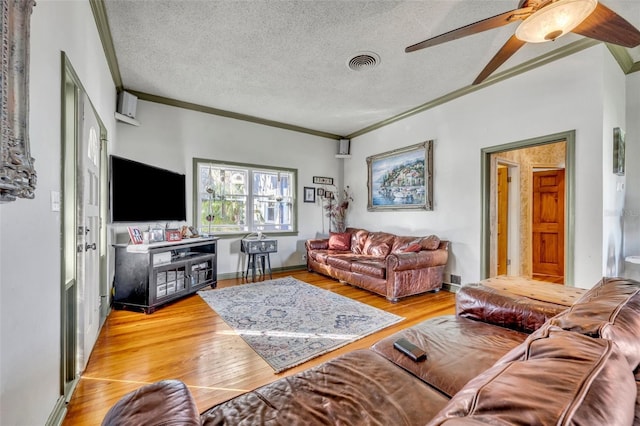 living room featuring ceiling fan, light hardwood / wood-style floors, a textured ceiling, and ornamental molding