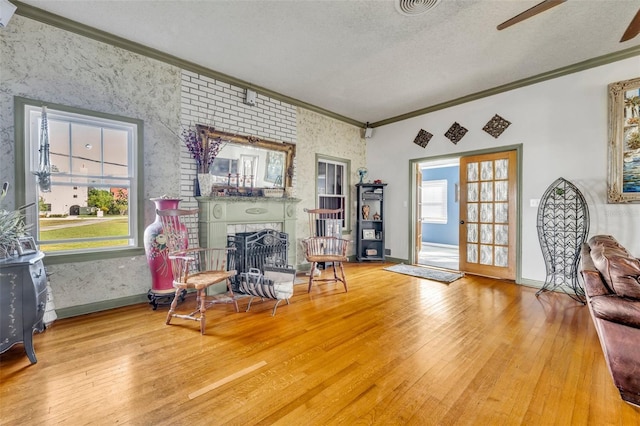 sitting room with a textured ceiling, light hardwood / wood-style floors, a wealth of natural light, and a large fireplace