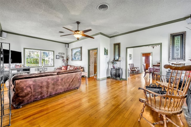 living room with ceiling fan, ornamental molding, a textured ceiling, and light wood-type flooring