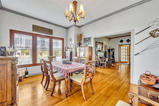 dining space featuring a chandelier, light wood-type flooring, and crown molding