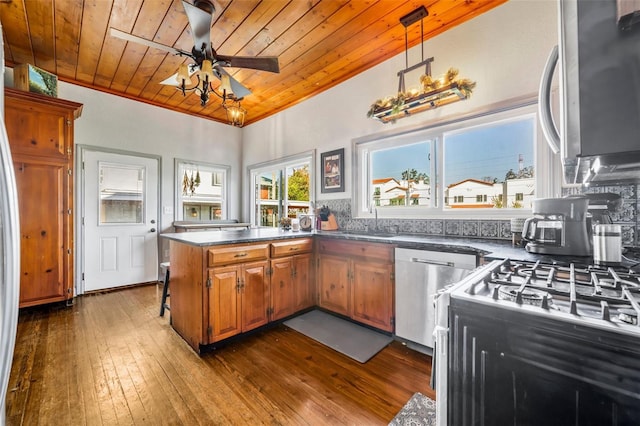 kitchen with kitchen peninsula, dark hardwood / wood-style flooring, stainless steel appliances, ceiling fan, and pendant lighting