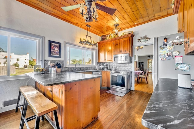 kitchen featuring decorative backsplash, appliances with stainless steel finishes, dark wood-type flooring, decorative light fixtures, and wooden ceiling