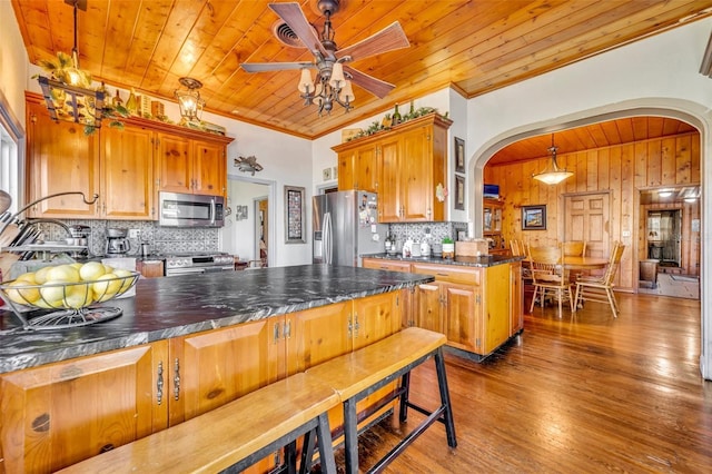 kitchen with decorative backsplash, dark wood-type flooring, hanging light fixtures, and appliances with stainless steel finishes