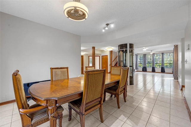 dining space featuring ceiling fan, light tile patterned flooring, and a textured ceiling