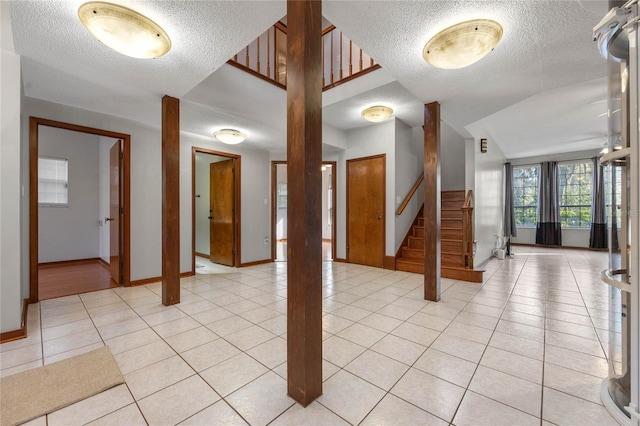 tiled foyer entrance featuring vaulted ceiling and a textured ceiling