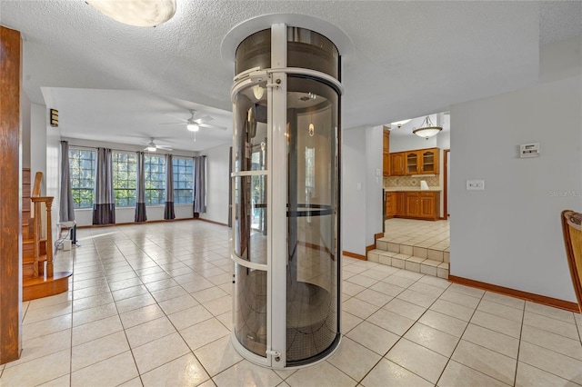 interior space featuring ceiling fan, light tile patterned floors, and a textured ceiling