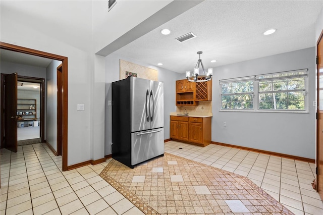 kitchen with a chandelier, a textured ceiling, decorative light fixtures, and stainless steel refrigerator