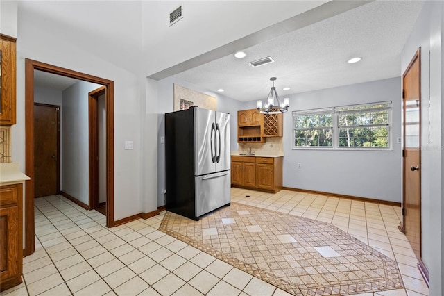 kitchen featuring hanging light fixtures, a notable chandelier, stainless steel fridge, a textured ceiling, and light tile patterned floors