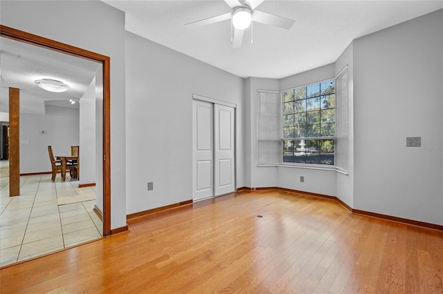 unfurnished bedroom with ceiling fan, light hardwood / wood-style floors, a textured ceiling, and a closet