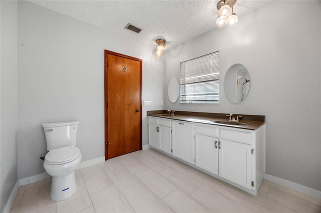 bathroom featuring vanity, a textured ceiling, and toilet