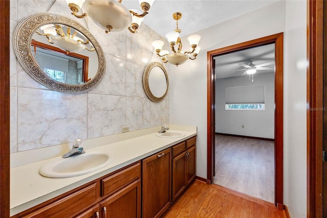 bathroom with hardwood / wood-style flooring, vanity, ceiling fan with notable chandelier, and tile walls