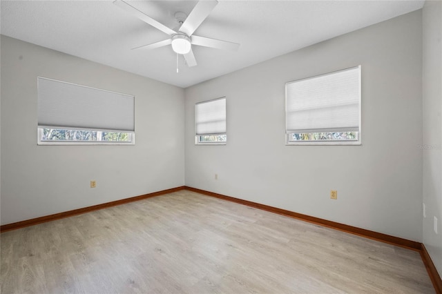 spare room with a wealth of natural light, ceiling fan, and light wood-type flooring