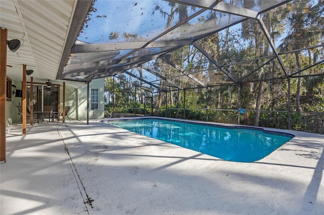 view of swimming pool with glass enclosure, ceiling fan, and a patio area