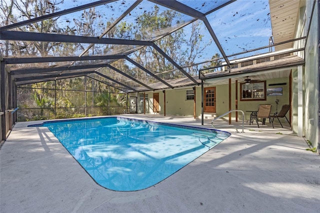 view of swimming pool with glass enclosure, ceiling fan, and a patio