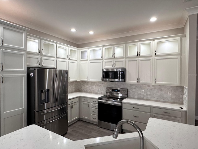 kitchen featuring white cabinetry, light stone countertops, ornamental molding, and appliances with stainless steel finishes