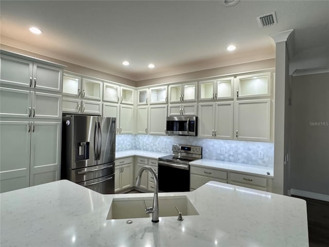 kitchen featuring sink, light stone countertops, stainless steel appliances, and tasteful backsplash