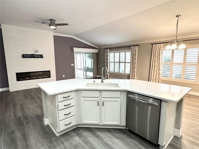 kitchen with sink, vaulted ceiling, stainless steel dishwasher, decorative light fixtures, and white cabinetry