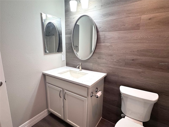 bathroom with vanity, toilet, and wood walls