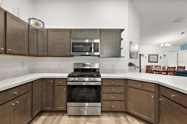 kitchen with kitchen peninsula, dark brown cabinets, stainless steel appliances, and light hardwood / wood-style floors