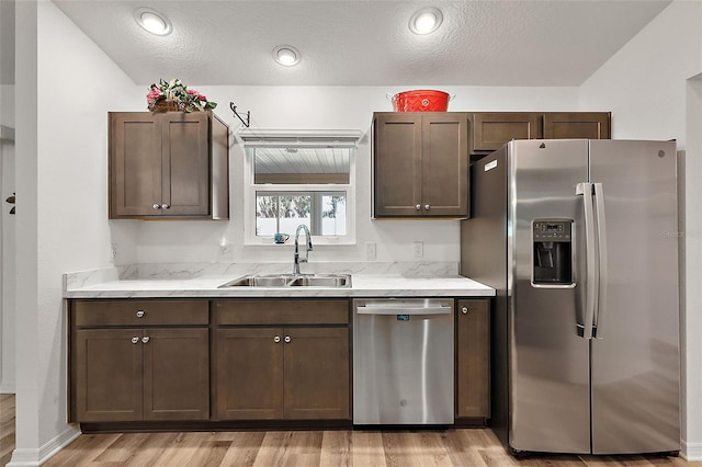 kitchen featuring appliances with stainless steel finishes, dark brown cabinetry, a textured ceiling, and sink