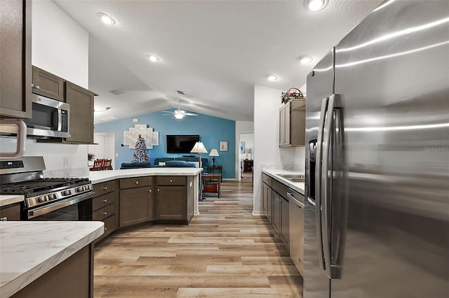 kitchen featuring vaulted ceiling, ceiling fan, light wood-type flooring, appliances with stainless steel finishes, and dark brown cabinetry