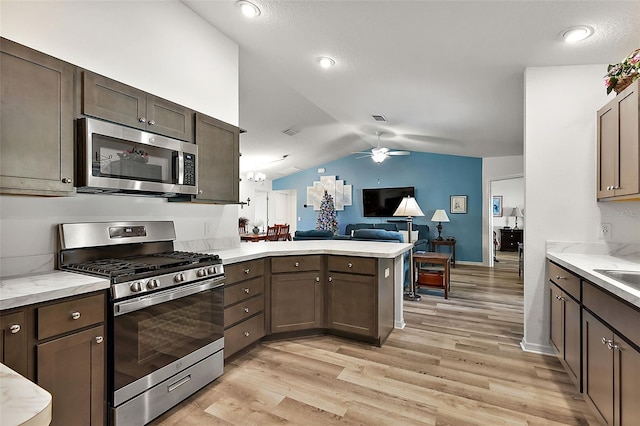 kitchen with kitchen peninsula, dark brown cabinetry, stainless steel appliances, vaulted ceiling, and light hardwood / wood-style floors