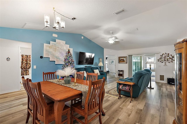 dining room with ceiling fan with notable chandelier, light wood-type flooring, and lofted ceiling