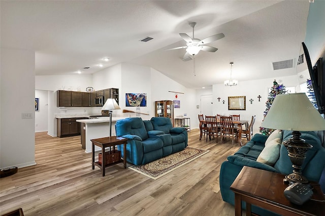 living room featuring ceiling fan with notable chandelier, light wood-type flooring, and lofted ceiling