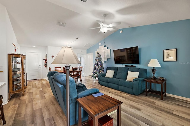 living room with ceiling fan, light wood-type flooring, and vaulted ceiling