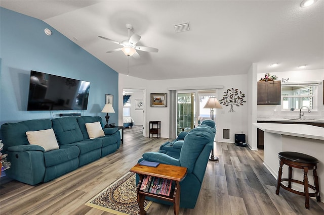 living room with ceiling fan, sink, vaulted ceiling, and light wood-type flooring