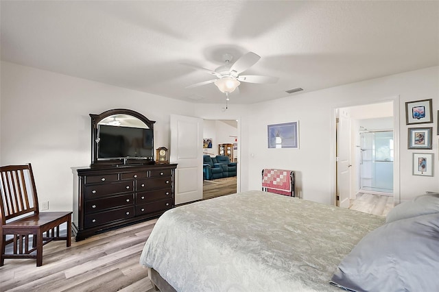 bedroom featuring ceiling fan, light wood-type flooring, and ensuite bath