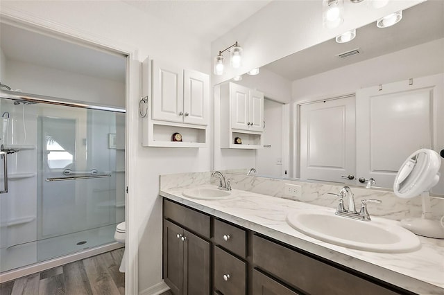 bathroom featuring hardwood / wood-style flooring, vanity, toilet, and walk in shower