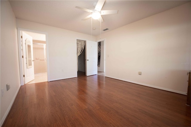 unfurnished bedroom featuring ensuite bathroom, ceiling fan, and dark wood-type flooring