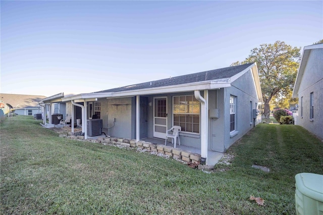 view of front of house with central AC and a front lawn