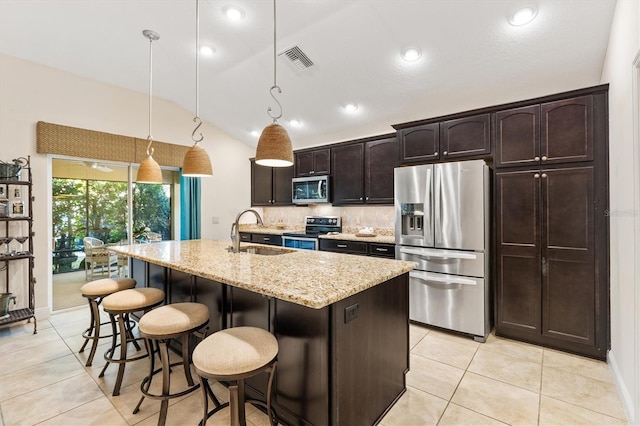 kitchen featuring sink, hanging light fixtures, lofted ceiling, a kitchen island with sink, and appliances with stainless steel finishes