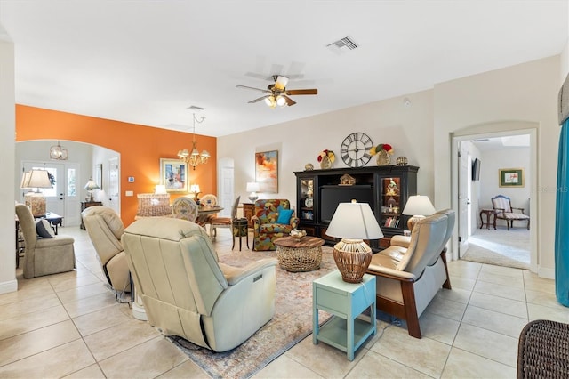 tiled living room with french doors and ceiling fan with notable chandelier