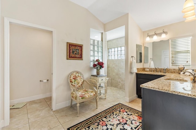 bathroom featuring tiled shower, vanity, tile patterned floors, and vaulted ceiling