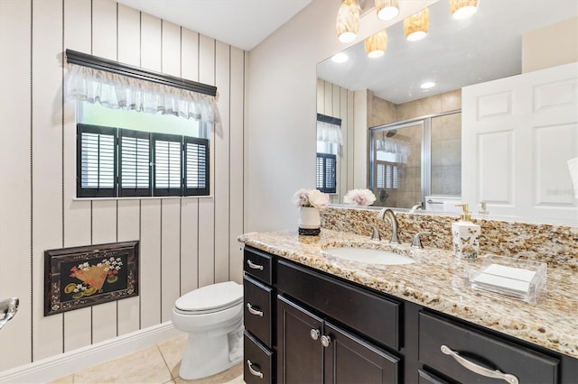 bathroom with vanity, wooden walls, tile patterned flooring, toilet, and an enclosed shower