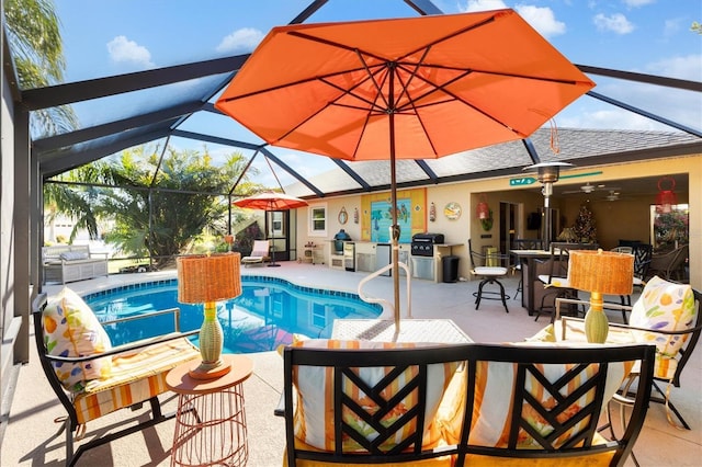 view of swimming pool featuring glass enclosure, a grill, exterior kitchen, and a patio