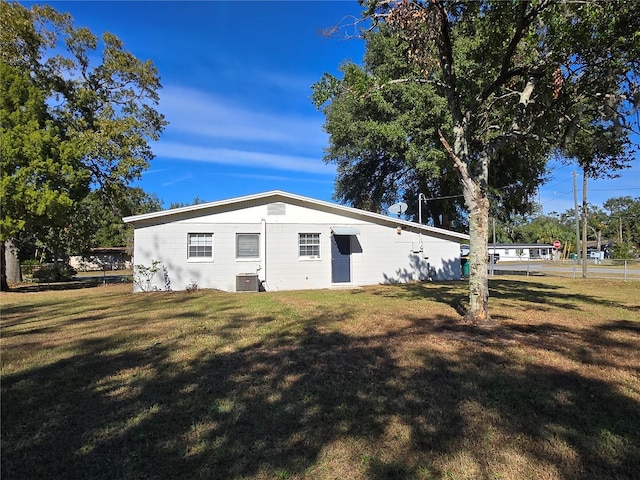 rear view of property with central AC unit and a yard