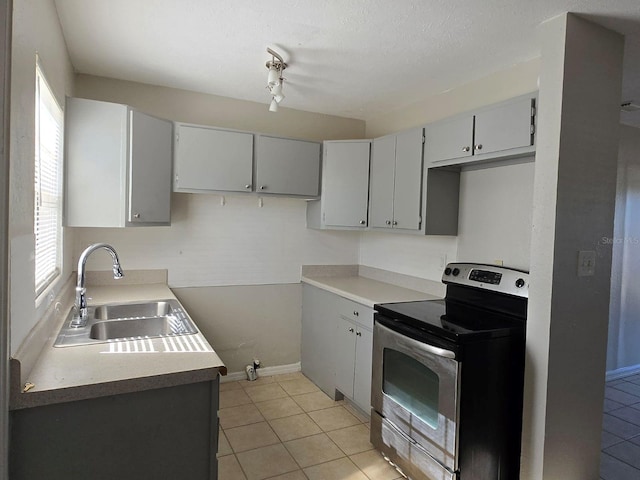 kitchen featuring light tile patterned floors, gray cabinets, stainless steel electric range oven, and sink