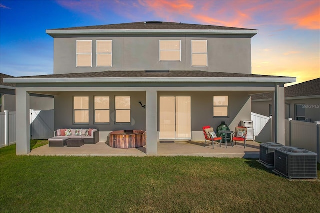 back house at dusk featuring a yard, cooling unit, a patio, and an outdoor hangout area